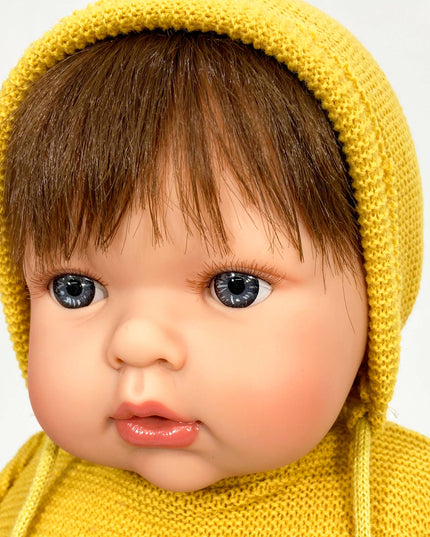 Baby wearing a yellow knitted hat and sweater on a white background