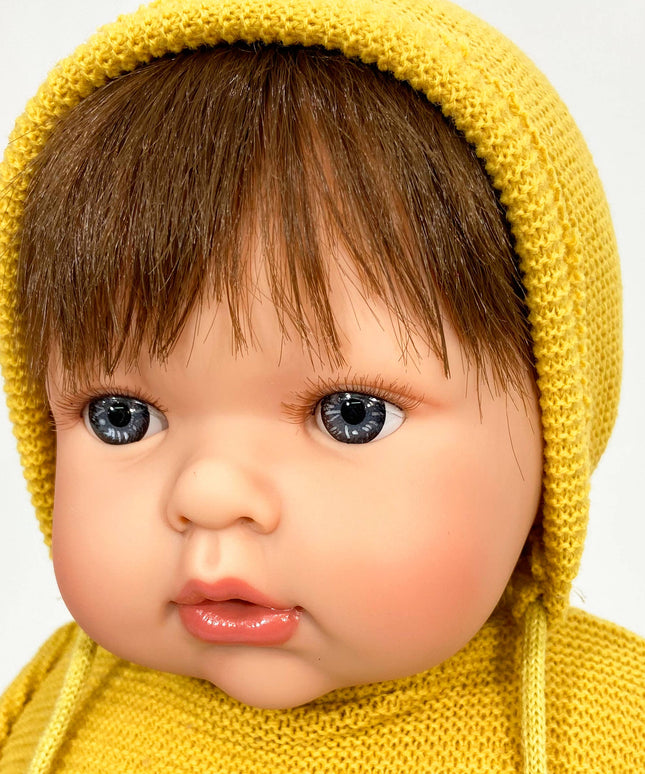 Baby wearing a yellow knitted hat and sweater on a white background