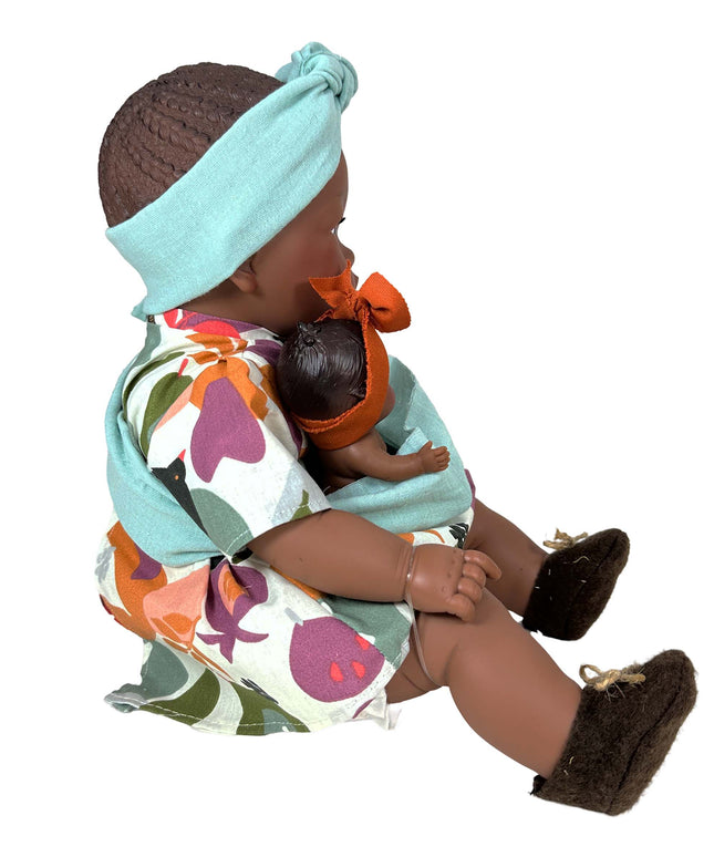 Doll holding a smaller doll with a colorful outfit and headband on a white background