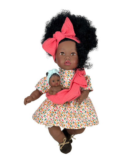 Doll with curly hair wearing a floral dress and pink headband, holding a smaller doll.