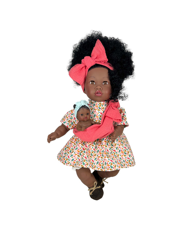Doll with curly hair wearing a floral dress and pink headband, holding a smaller doll.