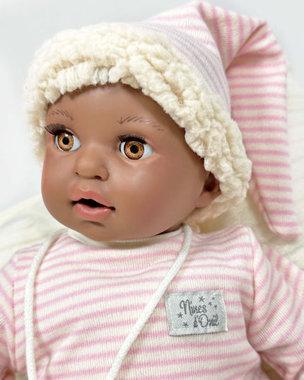 Baby doll with pink and white striped outfit and hat on a light gray background