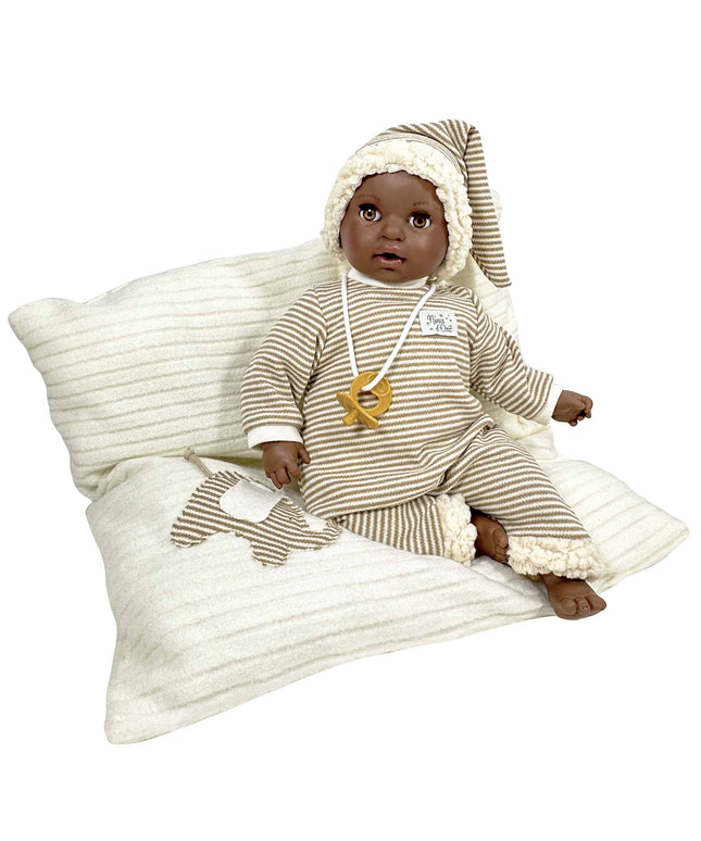 Baby doll in striped outfit sitting on a textured pillow with a white background