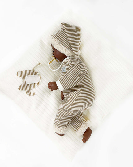 Baby in a striped onesie with a hood, lying on a white blanket.