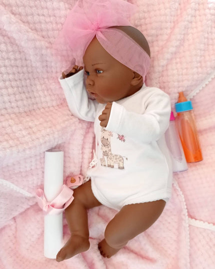 Baby doll wearing a white outfit with sequins on a pink textured blanket.