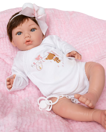 Baby doll wearing a white outfit with a bear design on a pink blanket