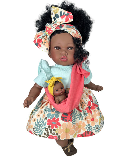 Doll holding a baby doll with floral dress and headband on a white background