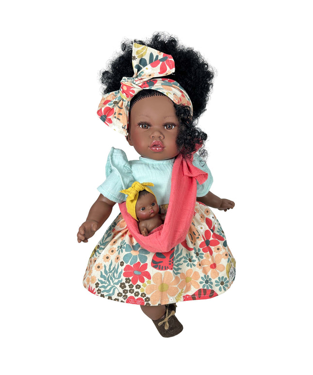 Doll holding a baby doll with floral dress and headband on a white background