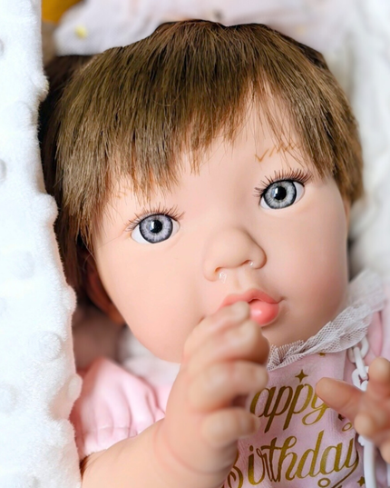 Close-up of a baby doll with blue eyes and a pink outfit on a white background