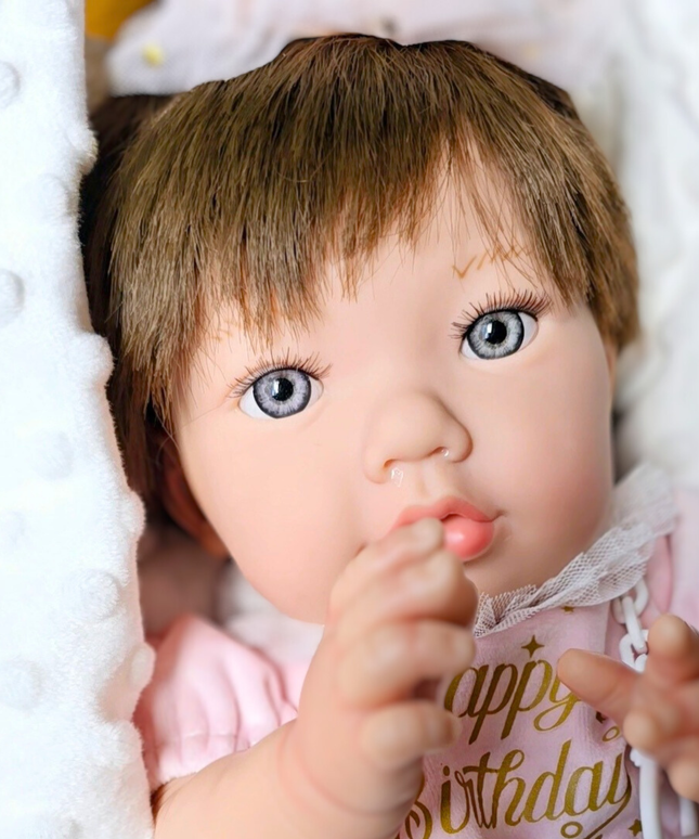 Close-up of a baby doll with blue eyes and a pink outfit on a white background