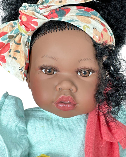 Doll with dark skin, curly hair, and a colorful headband on a white background