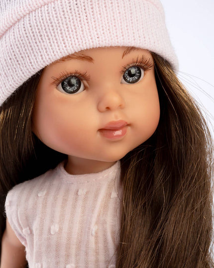 Close-up of a doll wearing a pink knitted hat and dress against a white background