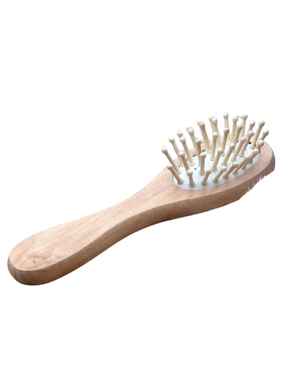 Set of wooden grooming tools including a brush, scrubber, and comb on a wooden surface.
