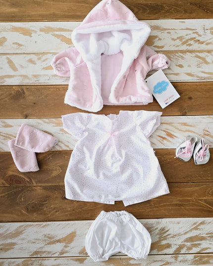 Baby clothing set including a pink hooded jacket, white dress, and bloomers on a wooden surface.