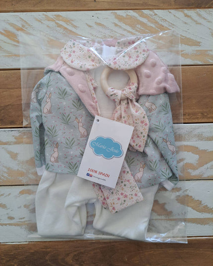 Children's clothing set with a hat, bib, and pants in clear packaging on a wooden surface.