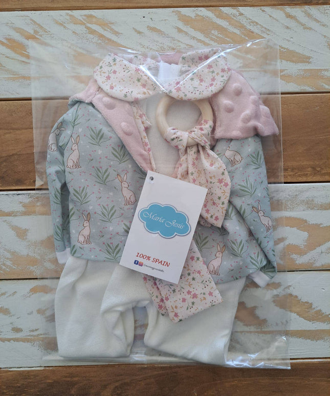 Children's clothing set with a hat, bib, and pants in clear packaging on a wooden surface.