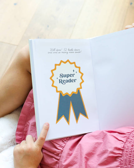 Person holding a book with a 'Super Reader' badge on a wooden floor.