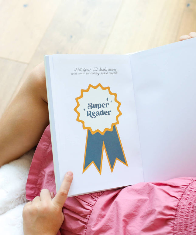 Person holding a book with a 'Super Reader' badge on a wooden floor.