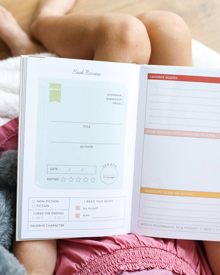 Person holding an open planner with a fluffy blanket and pillow in the background