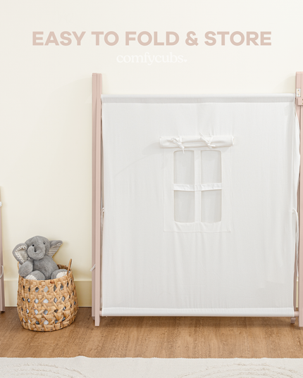 White tent with pink frame and mesh side panel, accompanied by a gray stuffed animal and wicker basket on a wooden floor.