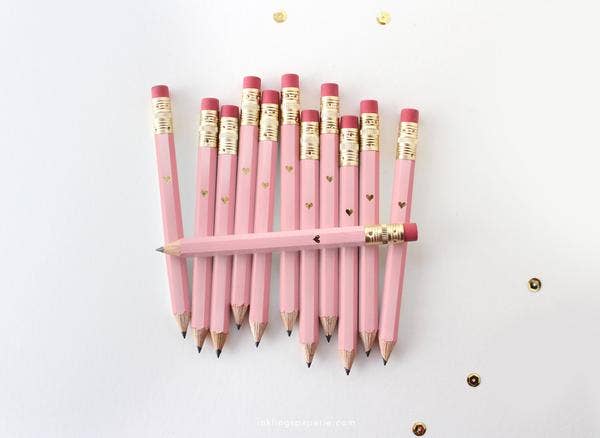 Pink pencils with gold accents arranged on a white background