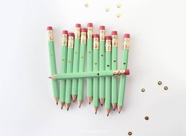 Mint green pencils with gold accents arranged in a fan on a white background