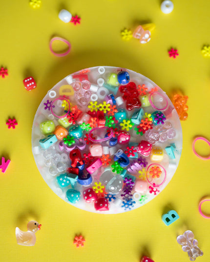 Colorful beads and small toys on a yellow background