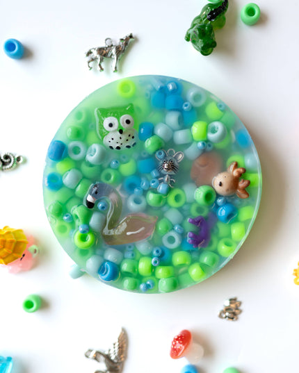 Decorative round object with colorful beads and small figurines on a white background