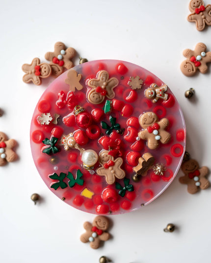Decorative resin coaster with gingerbread men and holly design on a white background