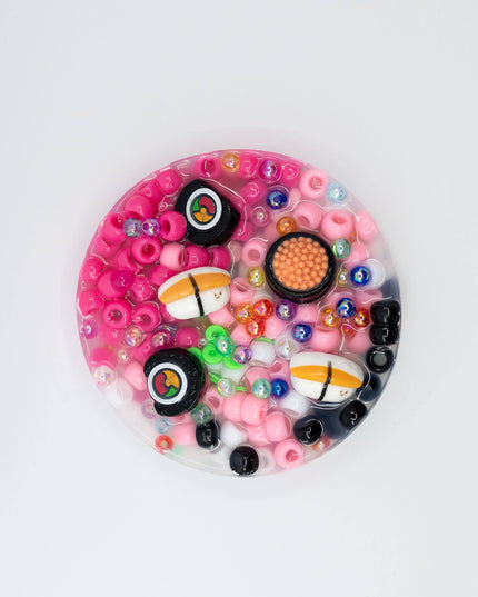 Circular object with pink and black design resembling sushi on a white background
