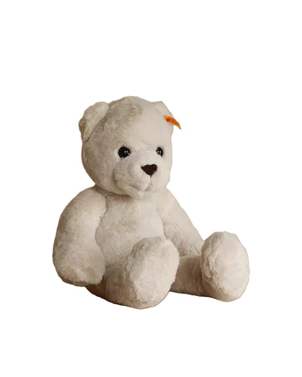 White teddy bear with a small orange tag on a wooden stool against a beige background