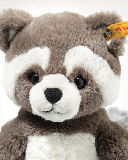 Plush raccoon toy with a visible Steiff tag on a white background
