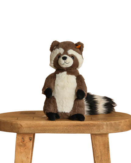 Plush raccoon toy on a wooden stool with a white background