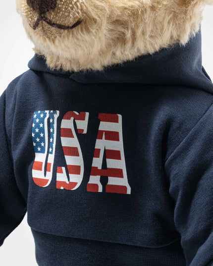 Teddy bear wearing a navy blue hoodie with 'USA' and an American flag design on a white background