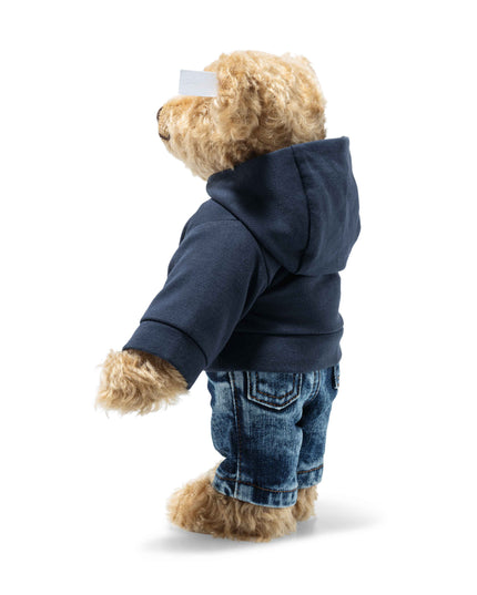 Teddy bear wearing a navy hoodie and blue jeans on a white background