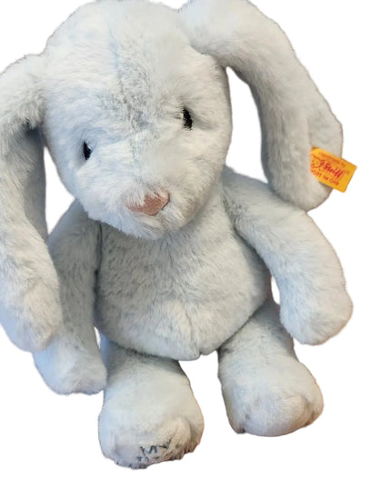 Plush toy bunny with a visible brand tag on a wooden surface
