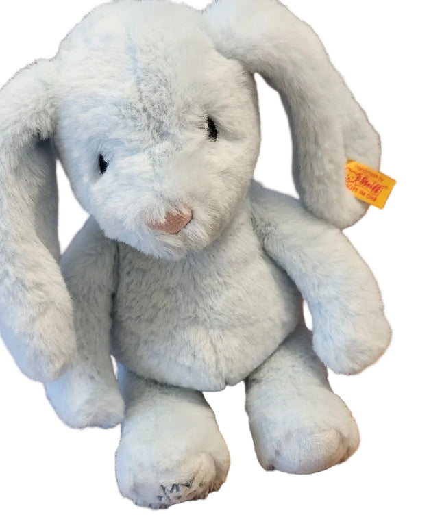 Plush toy bunny with a visible brand tag on a wooden surface