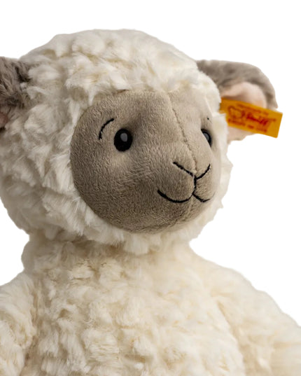 Close-up of a plush lamb toy with a visible Steiff tag on a white background
