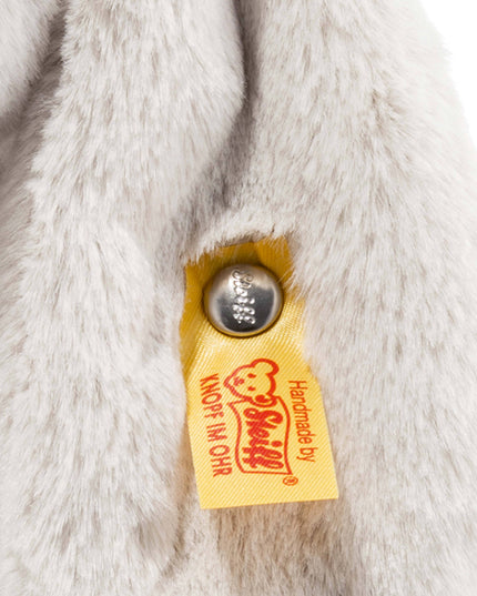 Close-up of a fluffy white fabric with a yellow tag featuring a logo and text.