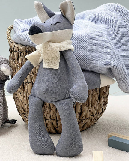 Gray plush toy with a scarf on a wicker basket with a blanket