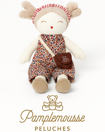 Stuffed toy with floral outfit and brown bag, featuring Pamplemousse Peluches logo.