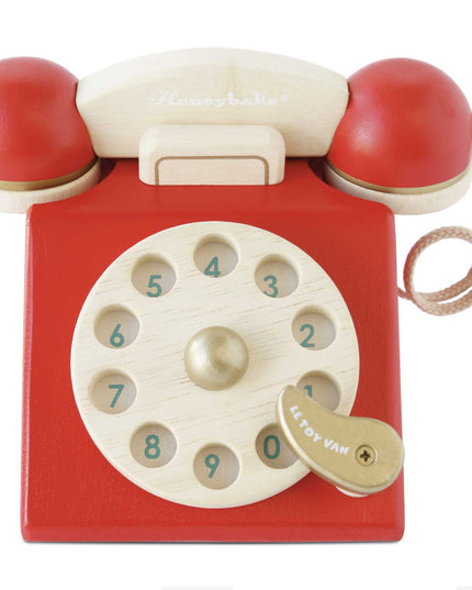 Red toy telephone with wooden rotary dial on a white background