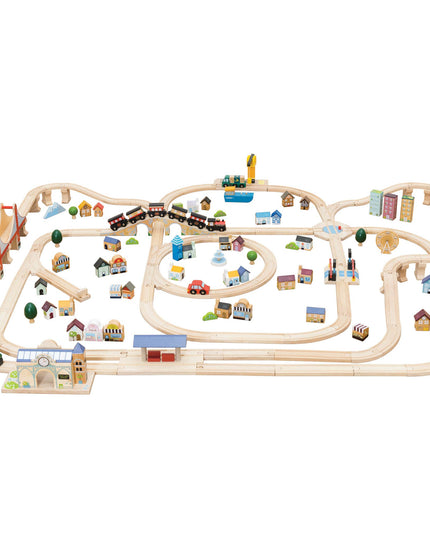 Wooden train track set with small buildings and trees on a white background