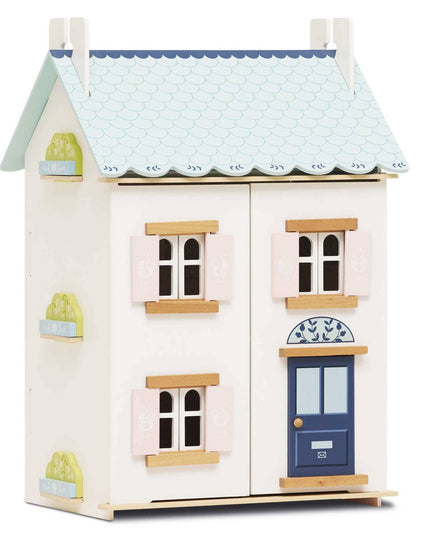 Wooden dollhouse with a blue roof and blue door on a white background