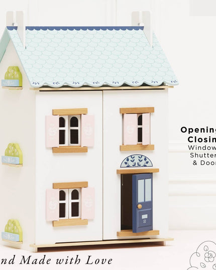 Toy dollhouse with opening windows, shutters, and door on a white background