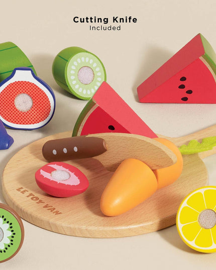 Wooden toy cutting board with colorful fruits and a knife on a beige background
