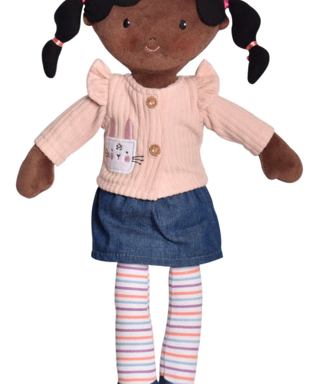 Plush doll with dark skin, black hair in pigtails, wearing a pink shirt, blue skirt, and striped socks on a white background.
